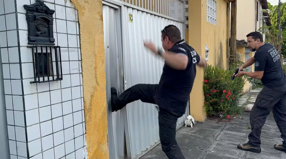 Policiais arrombando portão