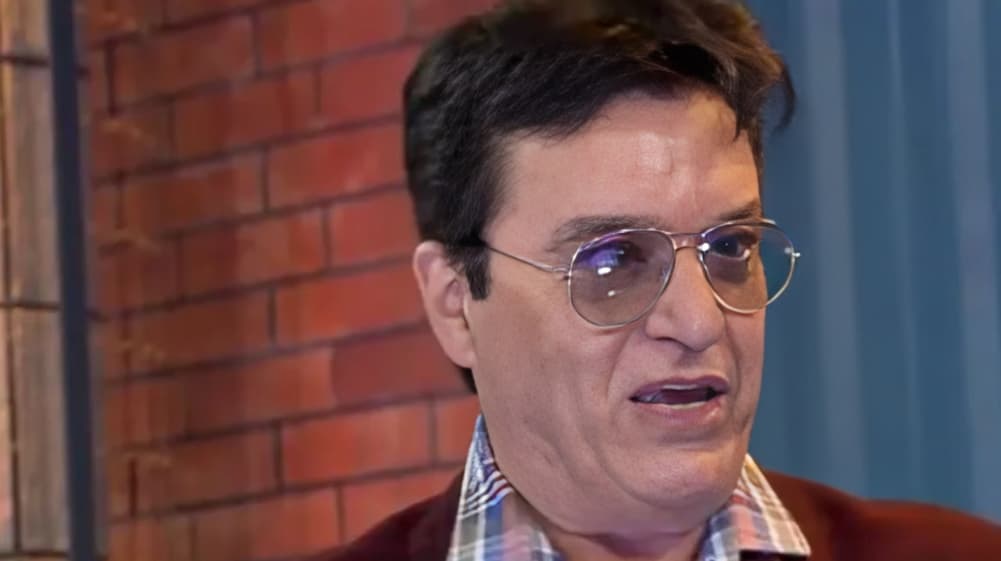Nahim de óculos, falando e olhando para o lado com expressão séria