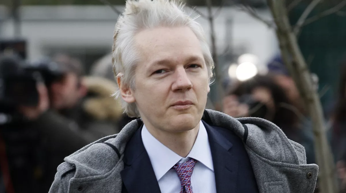 Julian Assange com expressão desconfiada e roupa social