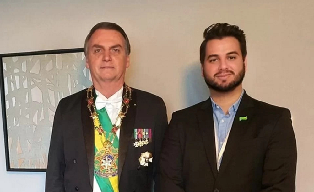 Jair Bolsonaro e Filipe Martins posando para foto lado a lado, o primeiro sério e o segundo com sorriso tímido