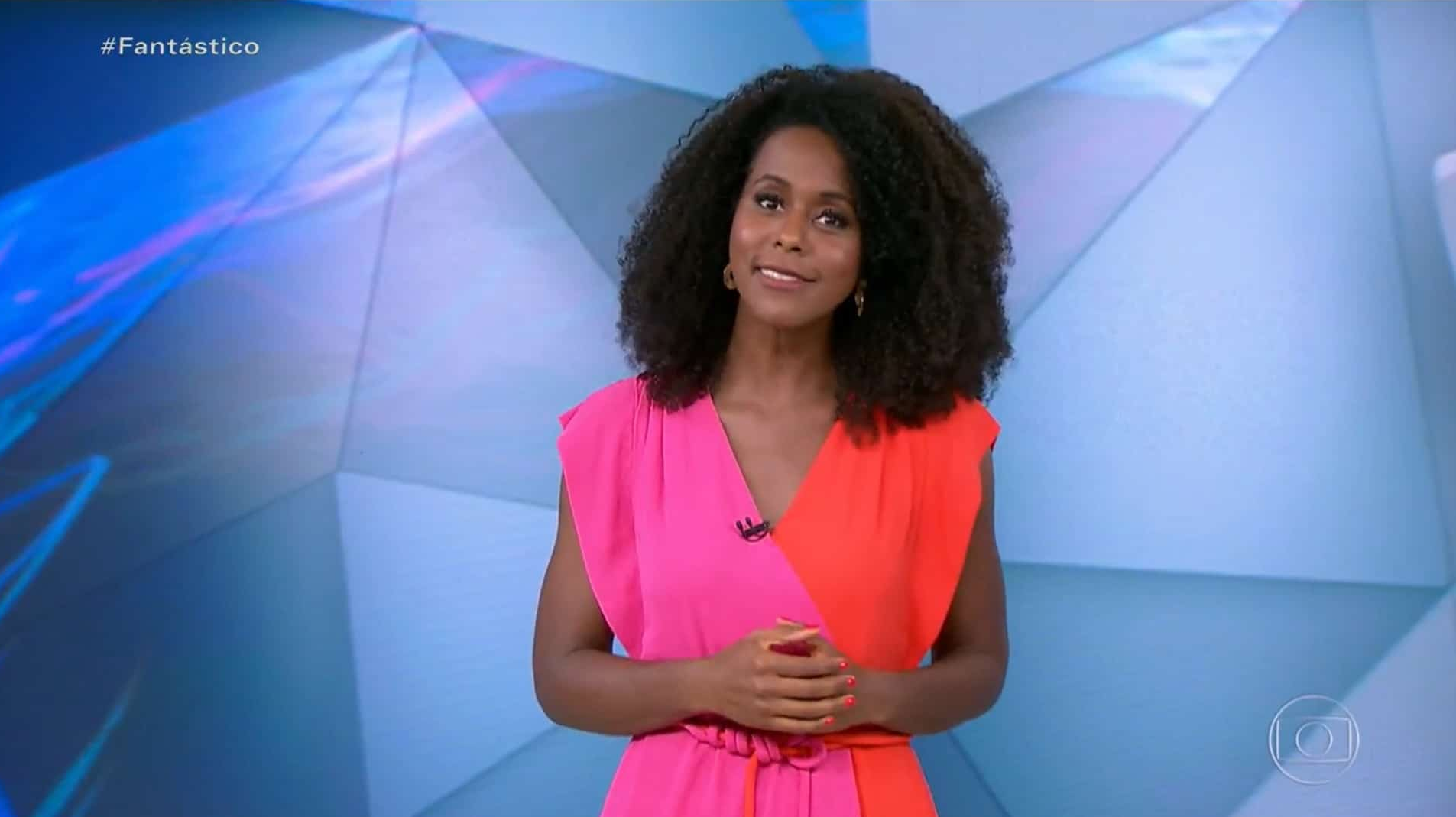 Maju Coutinho de roupa rosa e vermelha falando no estúdio do Fantástico