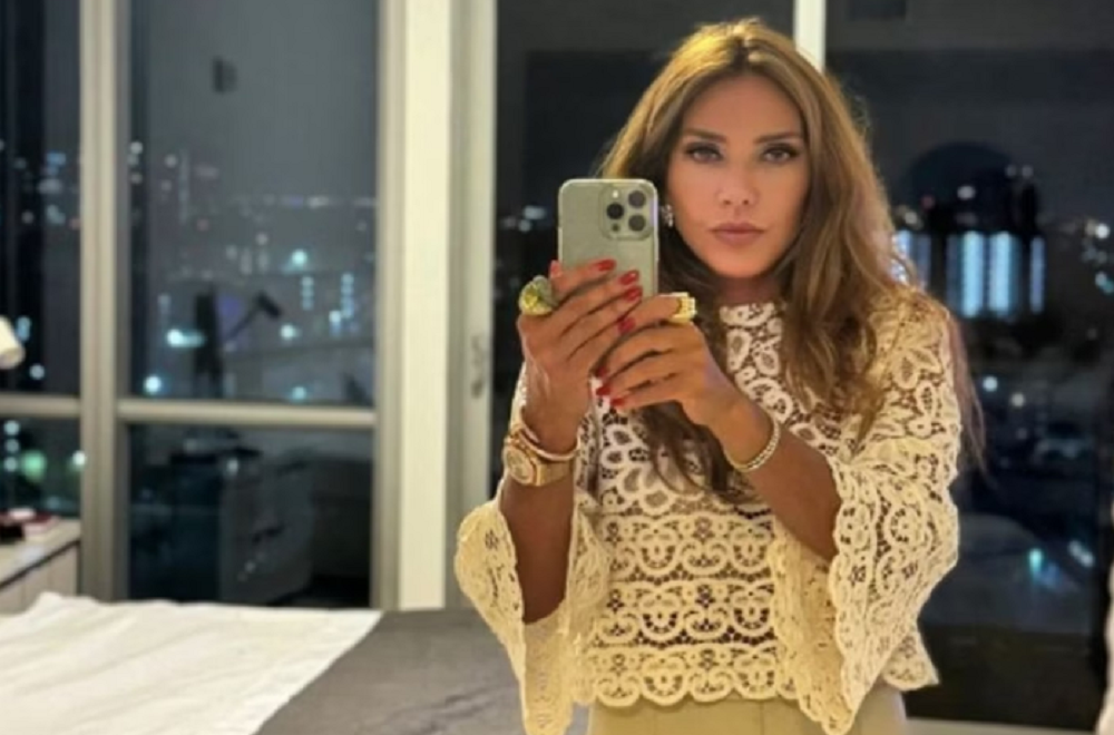 Flávia Rocha em foto no espelho, de roupa clara e cabelo solto