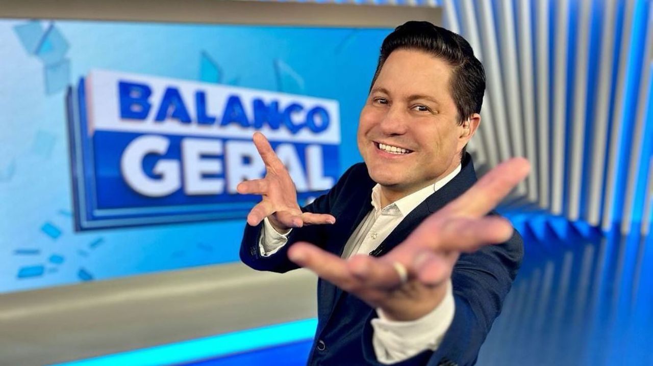 Eleandro Passaia no estúdio do Balanço Geral, sorrindo e apontando pra frente