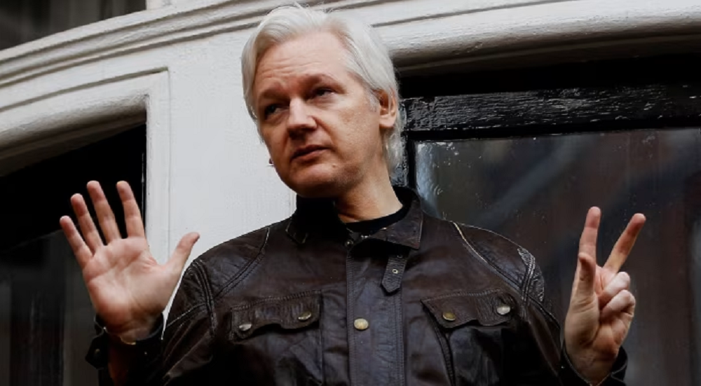 Julian Assange de roupa escura, sério, gesticulando