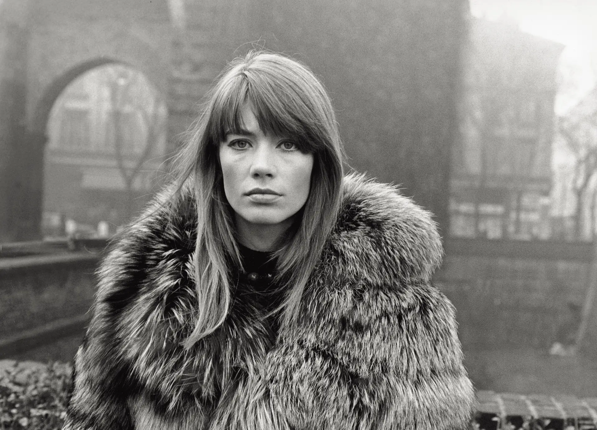 Françoise Hardy em foto antiga em preto e branco, séria, de cabelo solto e roupa de frio