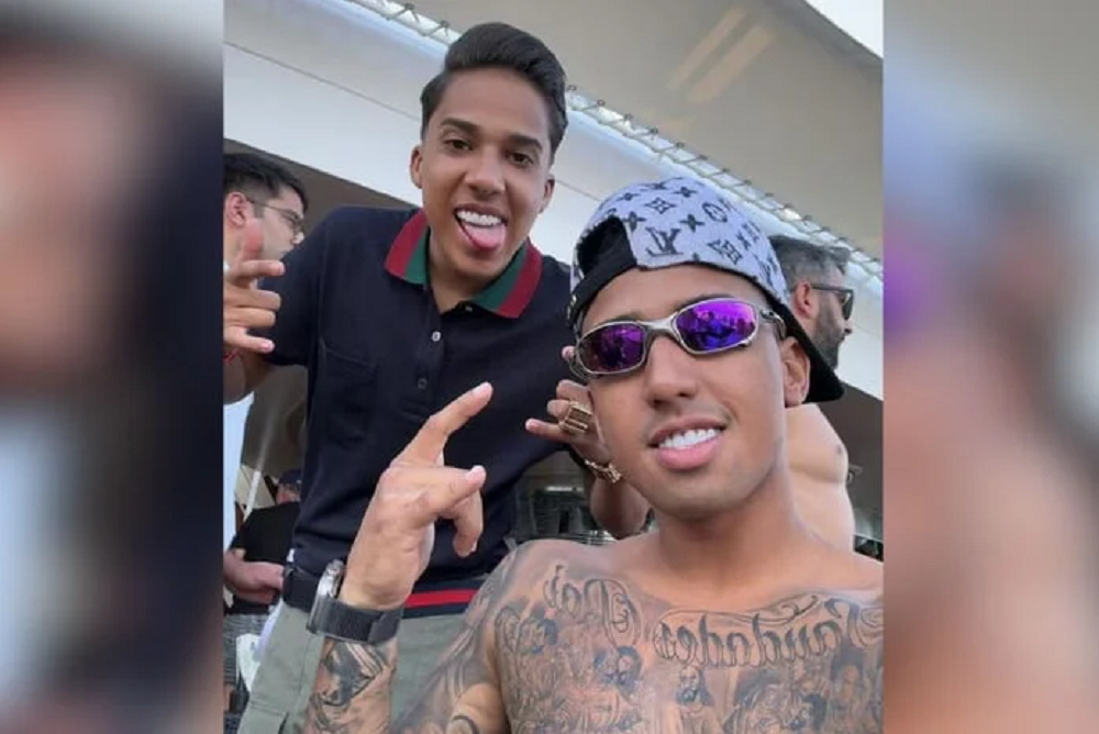 O influencer Nino, à esquerda, e o irmão Derik, sem camisa, ambos sorrindo e gesticulando
