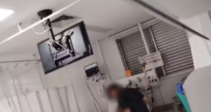 Pai perto de cama da filha em UTI de hospital