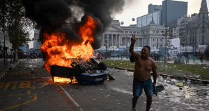 Homem andando sem camisa perto de carro pegando fogo