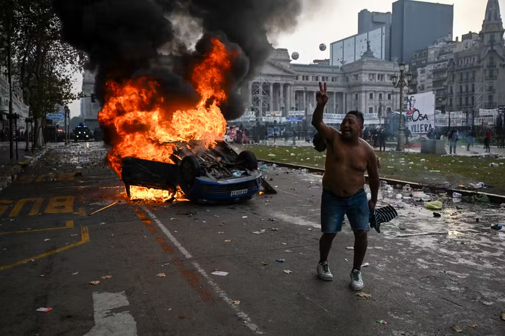 Homem andando sem camisa perto de carro pegando fogo
