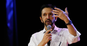 Ricardo Nunes de camisa social branca, falando em microfone e gesticulando