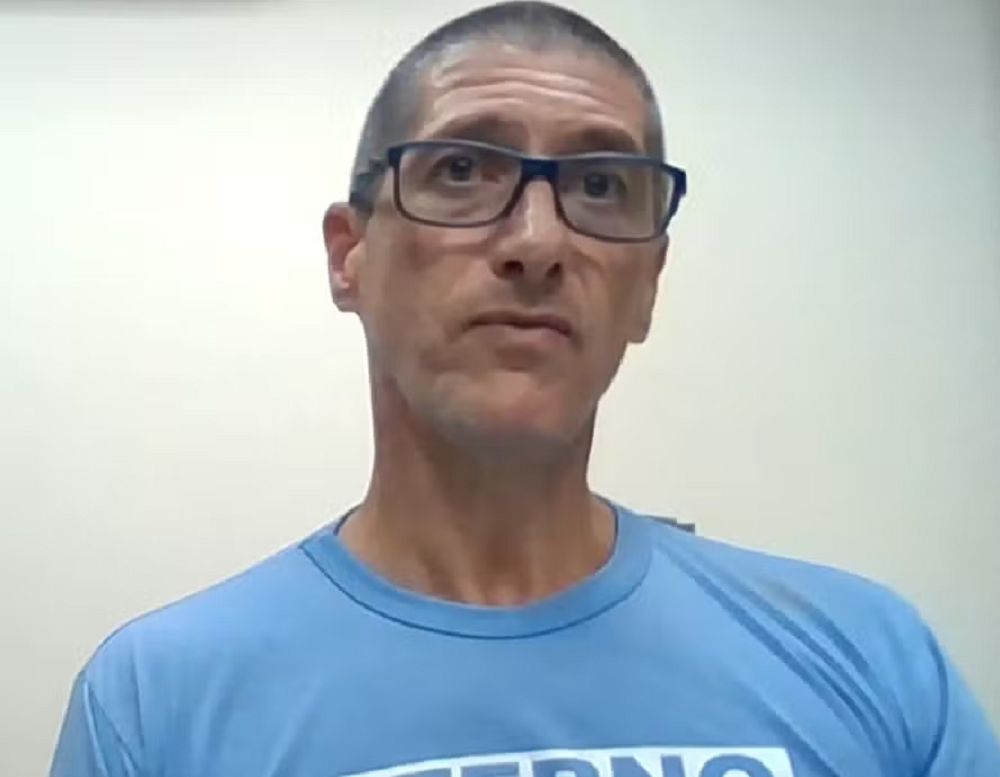 Ronnie Lessa de camiseta azul e óculos, com expressão séria