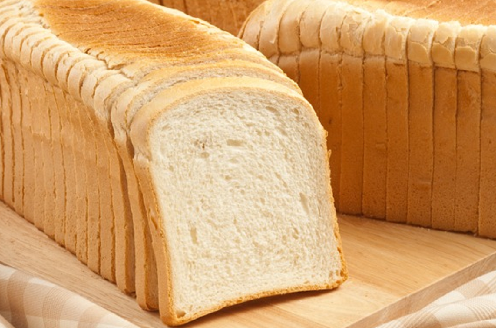Fatias de pão de forma enfileiradas em cima de tábua