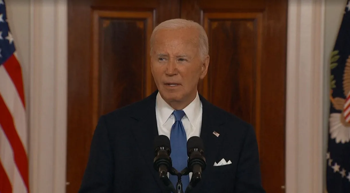 O presidente dos Estados Unidos, Joe Biden, falando em microfone, sério, de roupa social azul