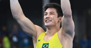 Arthur Nory de uniforme amarelo do Brasil, comemorando e sorrindo