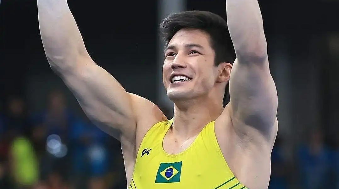 Arthur Nory de uniforme amarelo do Brasil, comemorando e sorrindo