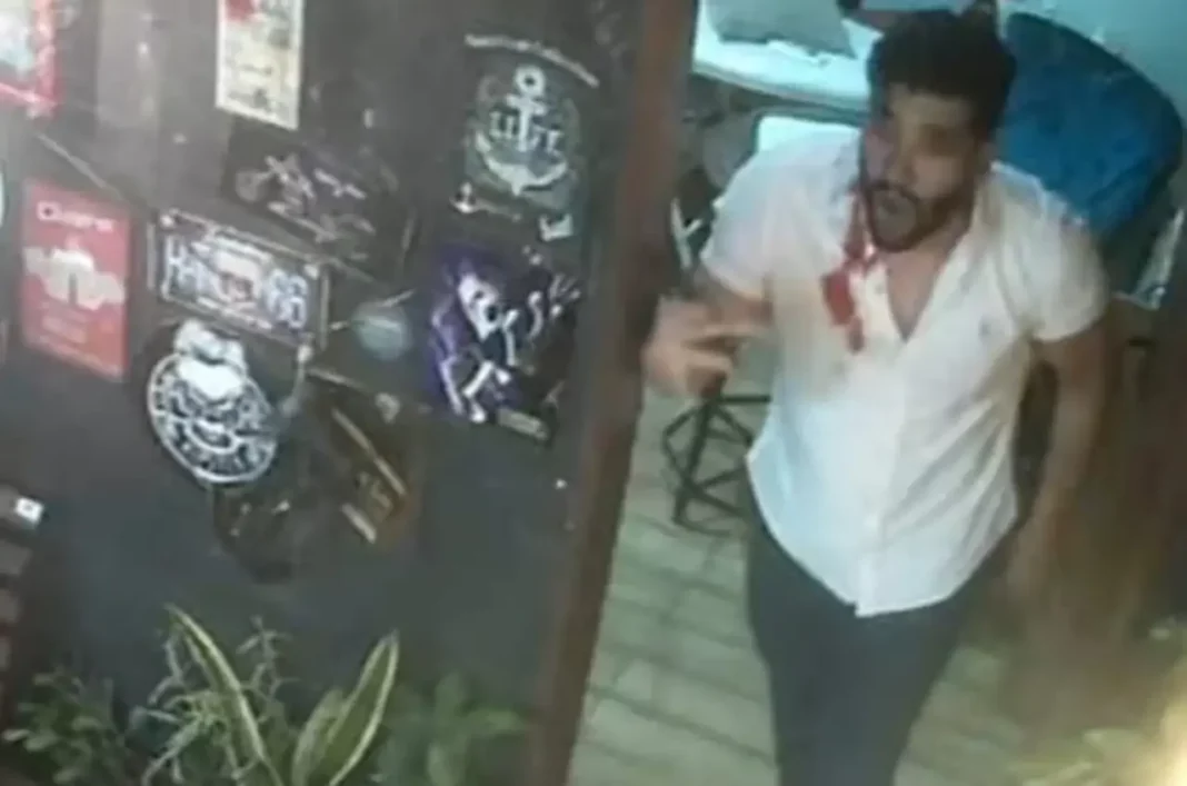 Vanderson Lima em barbearia, em pé, falando e gesticulando