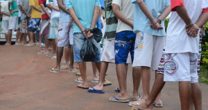 Presos de costas, sem mostrar os rostos, em fila