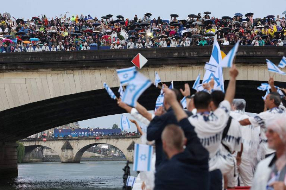 Pessoas levantando pequenas bandeiras de Israel perto do rio Sena