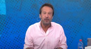 Emílio Surita falando para a câmera, no cenário do programa Pânico, de camisa social cor de rosa