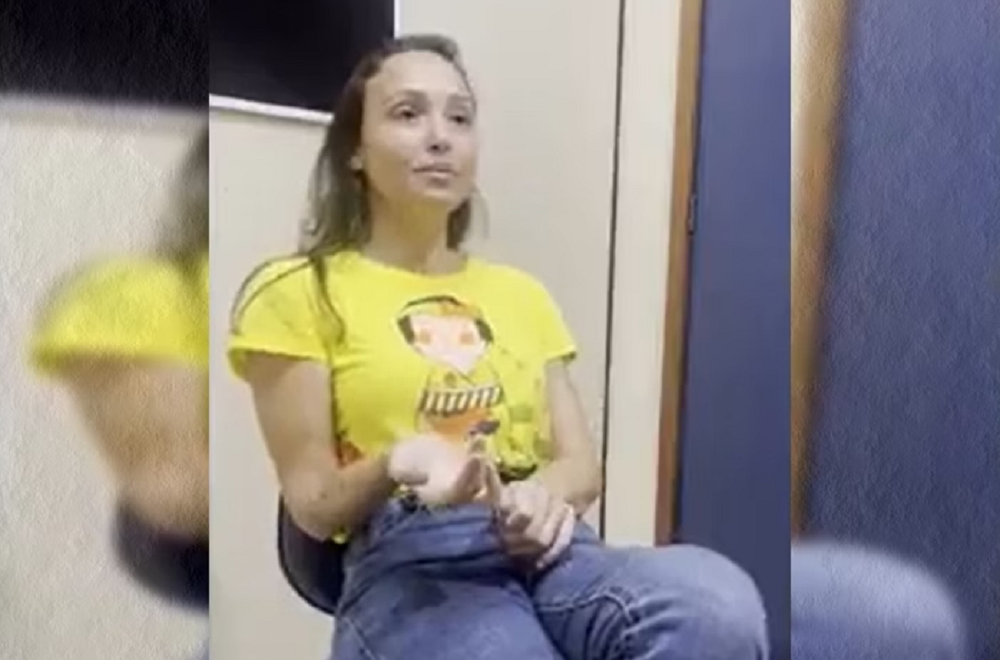 Júlia Andrade Cathermol Pimenta, acusada de assassinar empresário, de camiseta amarela e calça jeans, falando e gesticulando