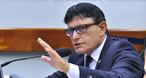 Deputado federal Éder Mauro sério, falando em microfone e gesticulando, de óculos