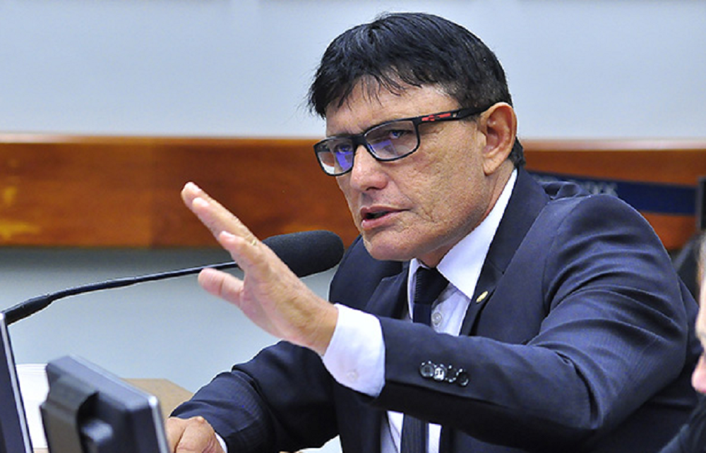 Deputado federal Éder Mauro sério, falando em microfone e gesticulando, de óculos