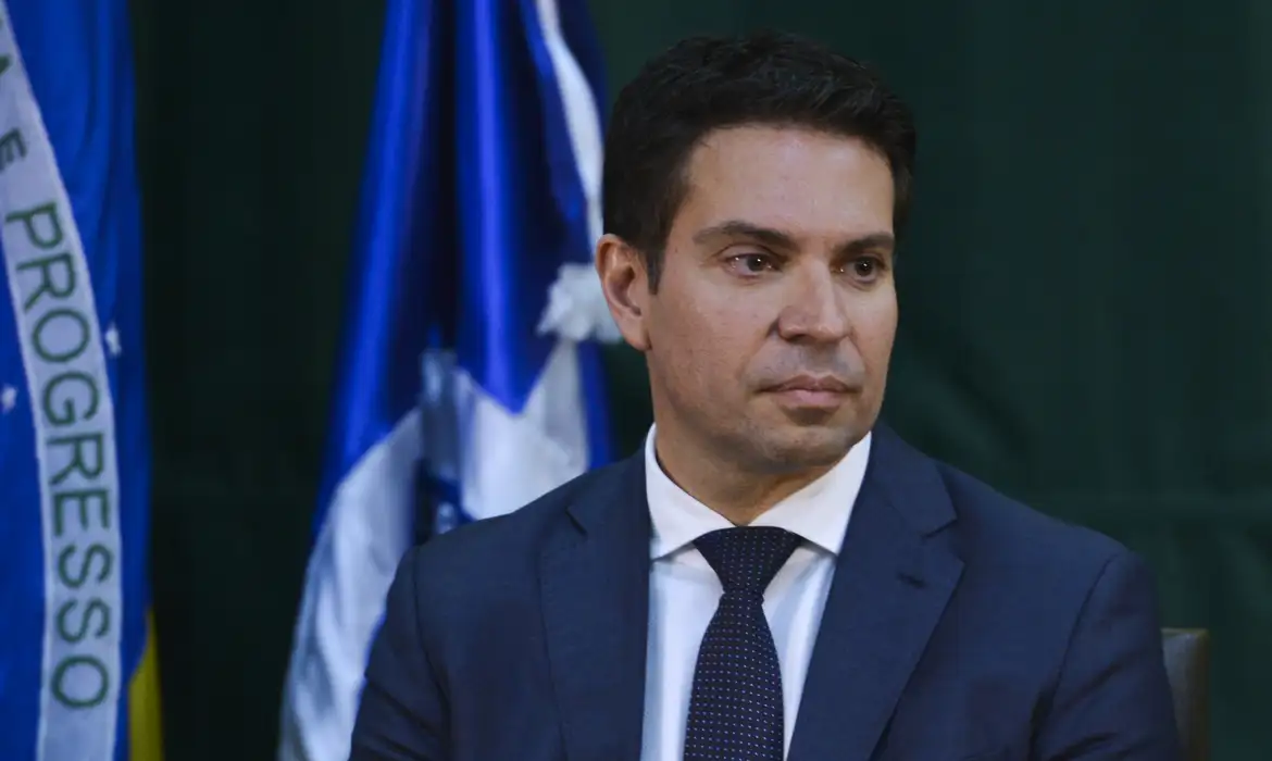 O ex-diretor da Abin Alexandre Ramagem (PL) com expressão triste, sem olhar para a câmera, com bandeiras ao fundo
