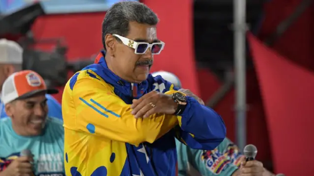 Nicolás Maduro de óculos, com os braços cruzados, sério, de perfil