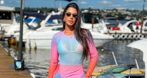 A influenciadora digital Aline Ferreira posando em píer, com roupa colorida e óculos escuros, séria, de cabelo solto