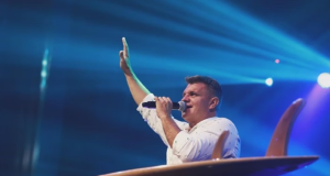 Pastor Rinaldo Pereira, da igreja evangélica Bola de Neve, de perfil, de roupa branca, falando em microfone