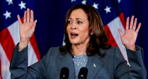A vice-presidente dos Estados Unidos, Kamala Harris, com expressão assustada, perto de bandeira norte-americana