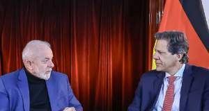 O presidente Luiz Inácio Lula da Silva e o ministro da Fazenda, Fernando Haddad conversando e se olhando, sentados e sérios