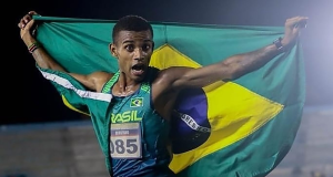 Maratonista Daniel Nascimento correndo com a bandeira do Brasil nas costas e expressão assustada