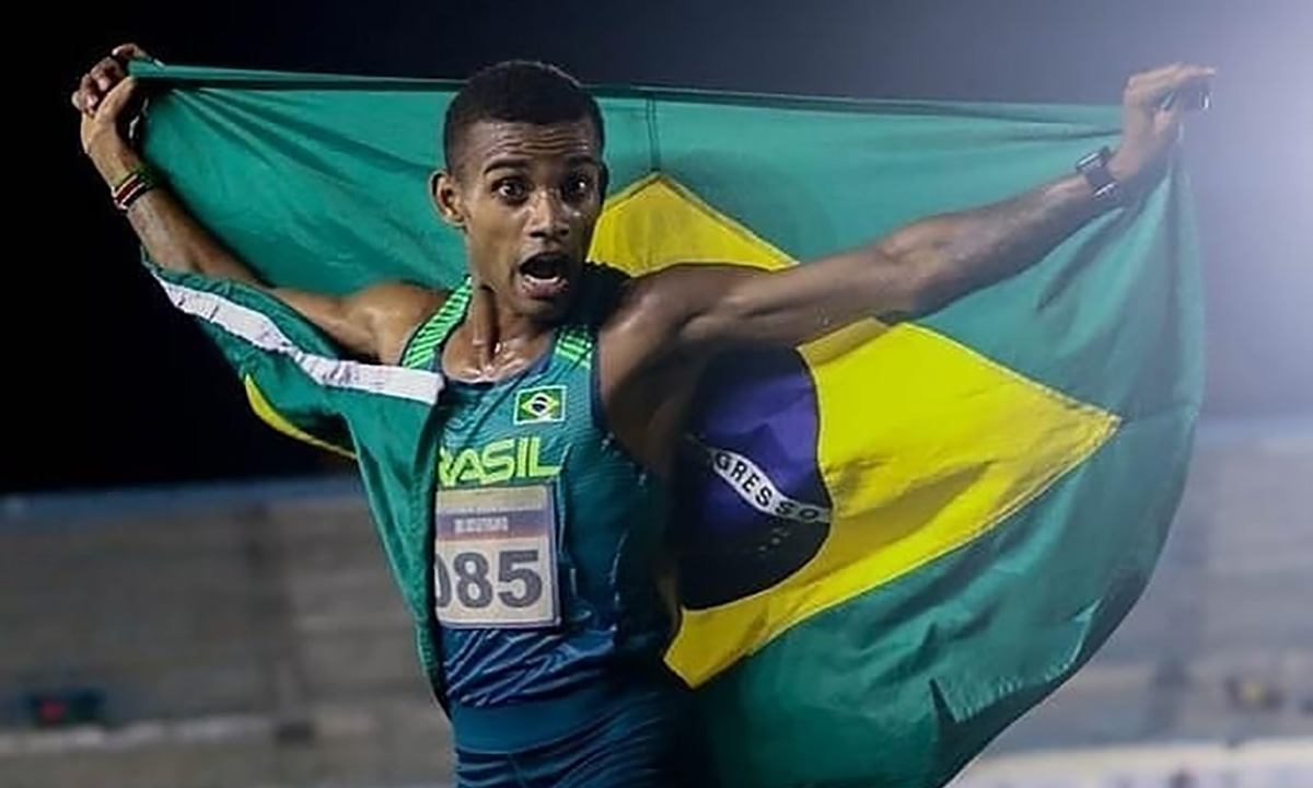 Maratonista Daniel Nascimento correndo com a bandeira do Brasil nas costas e expressão assustada