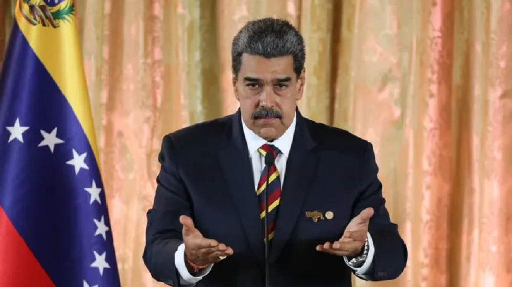 Nicolás Maduro olhando pra frente, sério, com as mãos abertas