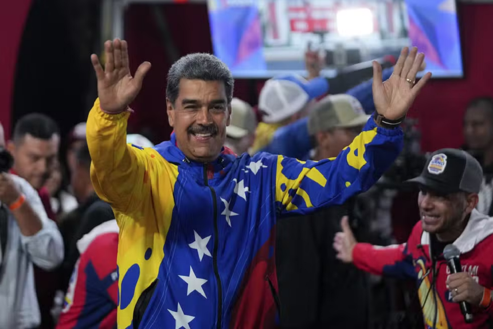 Nicolás Maduro com as roupas nas cores da bandeira venezuelana, sorrindo e acenando