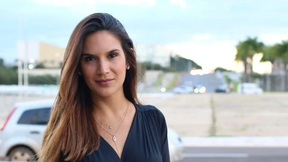 Renata Varandas de roupa escura e cabelo solto, posando sem sorrir