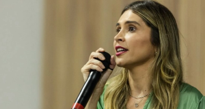 A vereadora Josie Dartora (PV) de perfil, de cabelo solto e roupa verde, falando em microfone