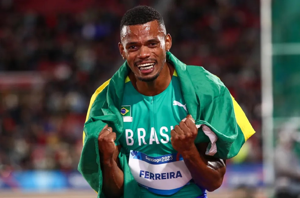 Fernando "Balotelli", do decatlo, sorrindo e comemorando, com uniforme e bandeira do Brasil