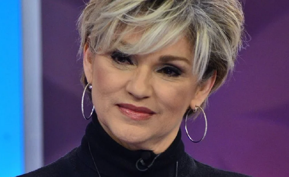 A apresentadora e atriz Andréa Nóbrega séria, sem olhar para a câmera, com roupa preta e brincos de argola