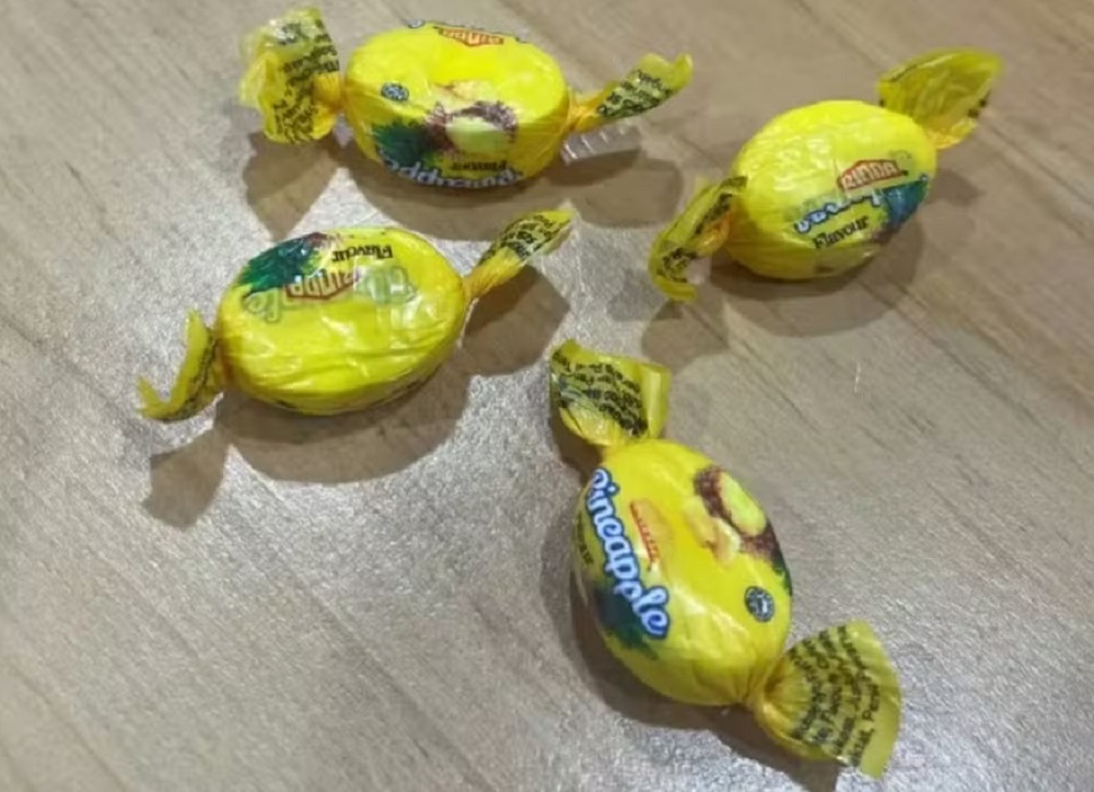 Quatro balas com embalagens amarelas em superfície que parece de madeira