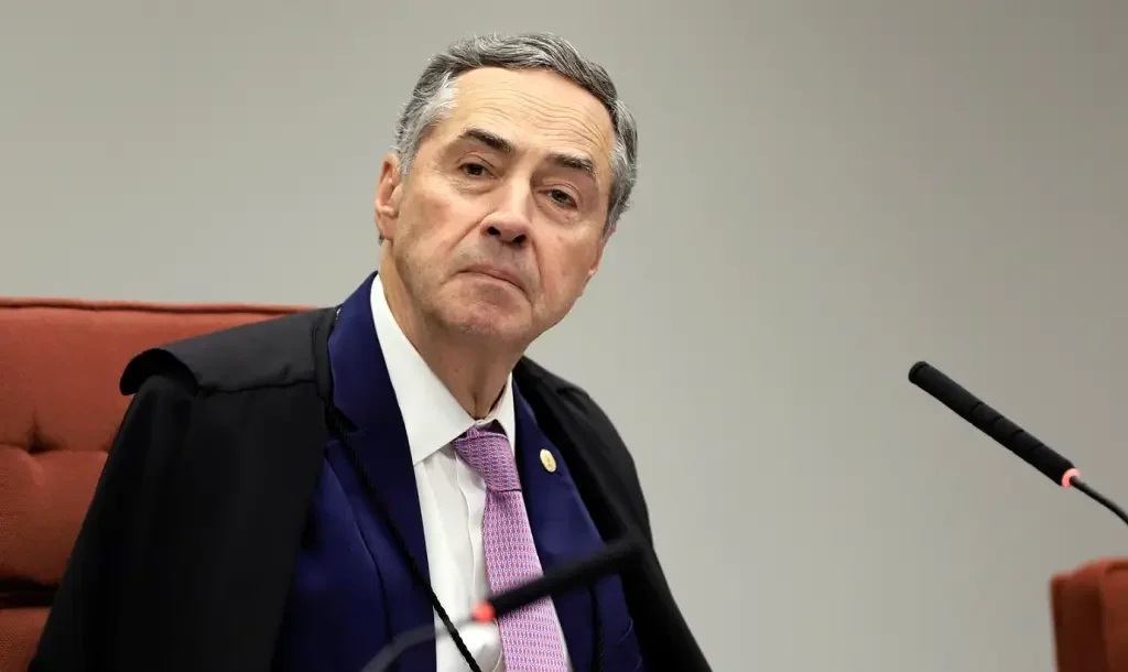 O presidente do Supremo Tribunal Federal (STF), Luís Roberto Barroso com expressão séria, perto de microfones