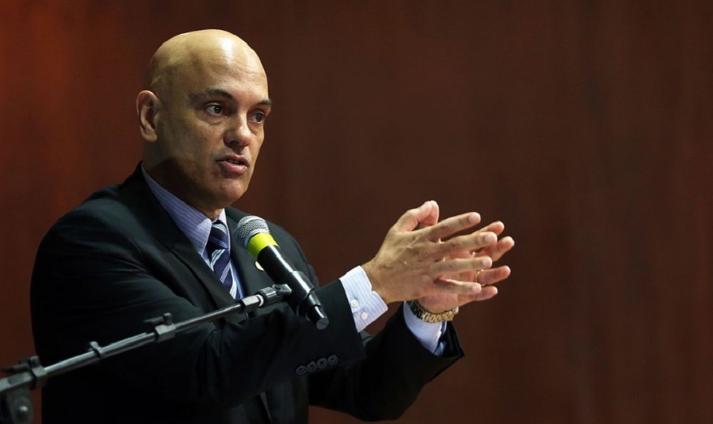 Alexandre de Moraes falando em microfone e gesticulando, sério