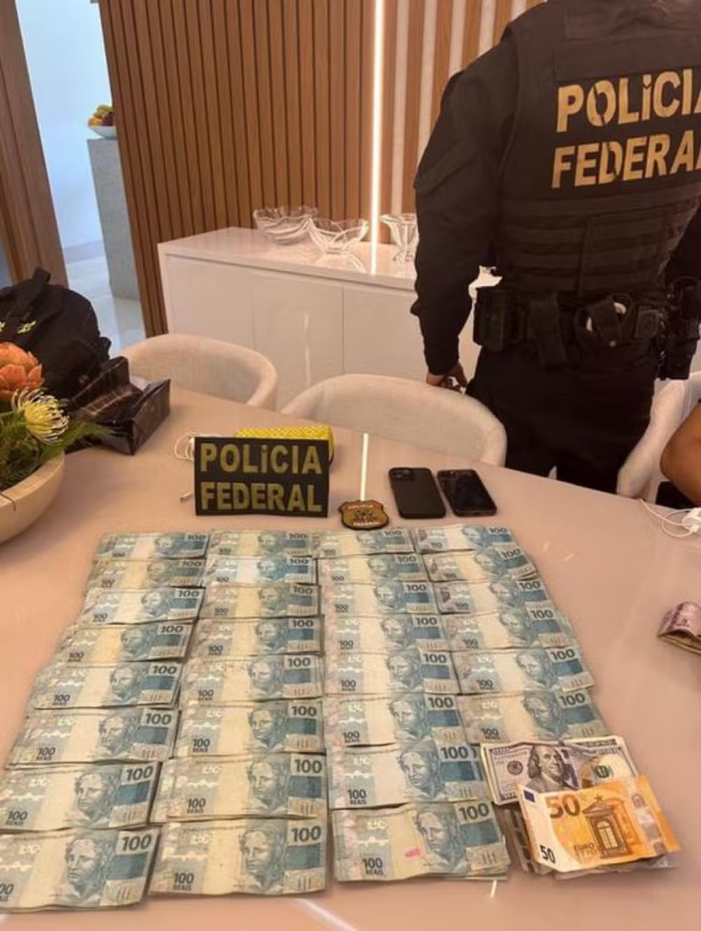 Dinheiro apreendido na casa de Wanderlei Barbosa, em cima da mesa, com agentes da PF ao redor