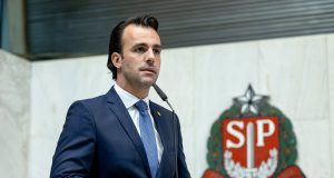 O deputado estadual Lucas Bove (PL-SP) em pé, sério, falando em microfone, sem olhar para a câmera