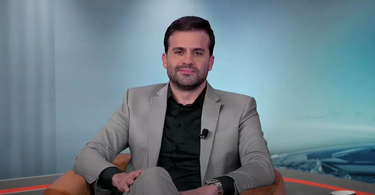 Pablo Marçal, candidato do PRTB a comandar a cidade de São Paulo, de roupa bege e preta, sentado, posando para foto com sorriso tímido