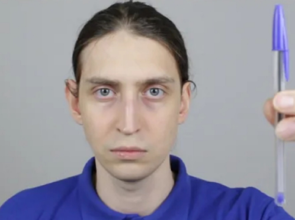 Felca de camisa azul segurando caneta, sério