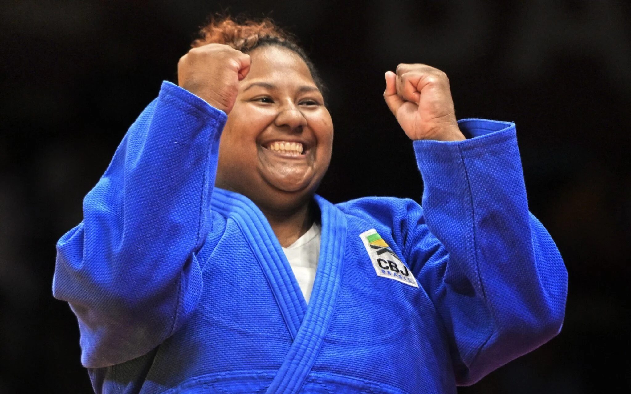 Bia Souza, de azul, comemorando e sorrindo