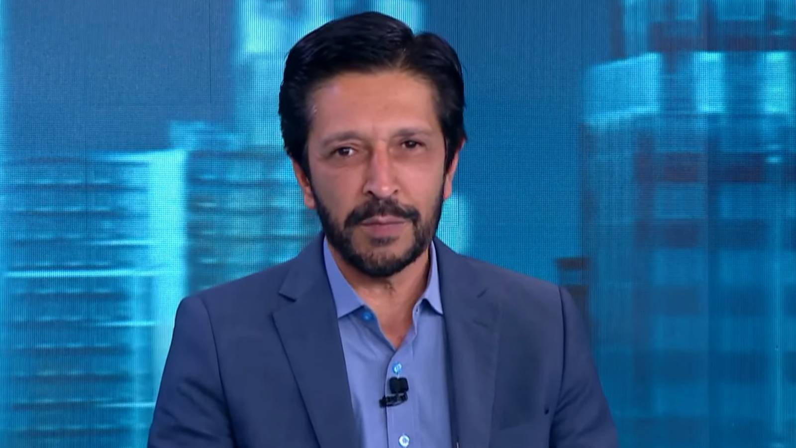 Ricardo Nunes de roupa social azul, olhando para frente, sério