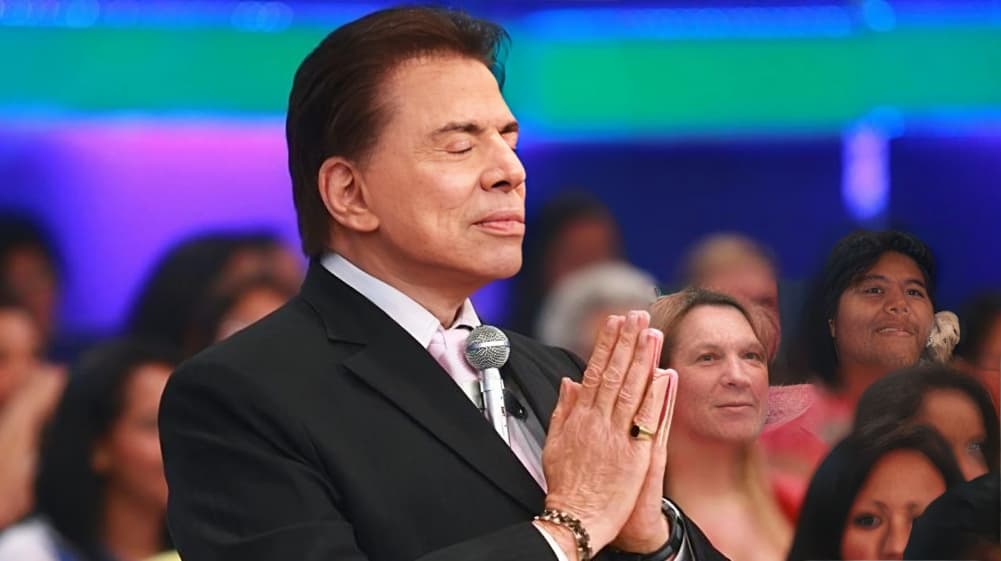 Silvio Santos de olhos fechados, em posição de oração